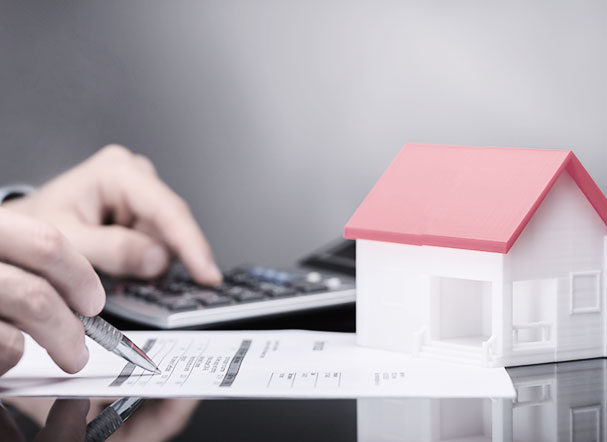  Cropped image of hands writing and on the left there is a toy house object