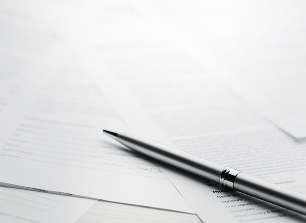 Silver pen positioned above several A4 sheets of white paper