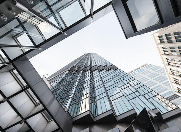Lower view of a building with a metallic structure and glass panels with a bluish undertone